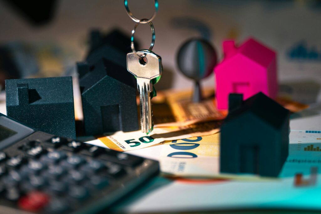 Imagem de chaves, miniaturas de residências, calculadora e notas de dinheiro, fazendo a relação entre investimento imobiliário e rentabilidade