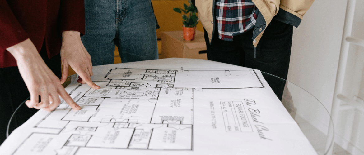 três pessoas olhando a planta de um imóvel - casarão imóveis - comprar imóvel na planta