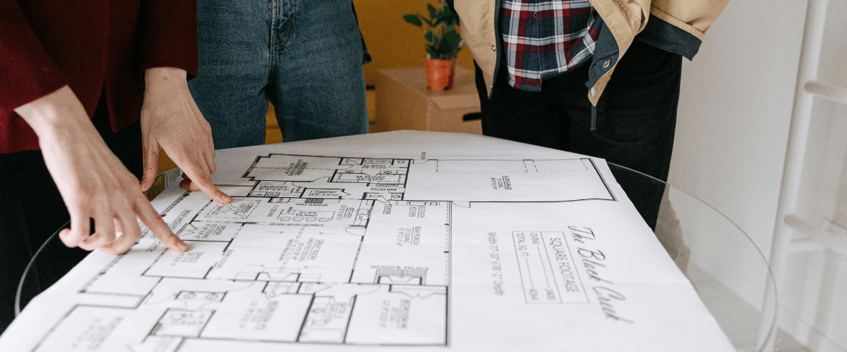 três pessoas olhando a planta de um imóvel - casarão imóveis - comprar imóvel na planta