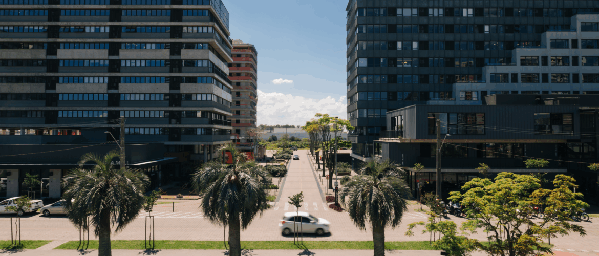 imagem do parque una com dois prédios grandes em cada uma das laterais e uma rua ensolarada no meio
