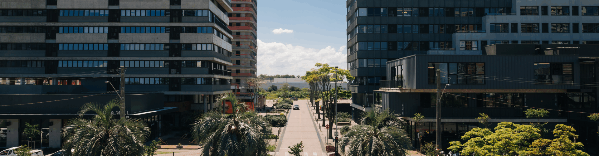 imagem do parque una com dois prédios grandes em cada uma das laterais e uma rua ensolarada no meio