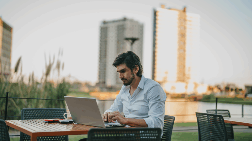 homem sentado trabalhando em um notebook com os prédios do parque una de fundo